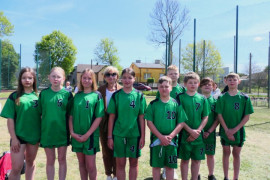 Grupa młodych zawodników na murawie boiska. Młodzi ludzie ubrani są w zielone koszulki 