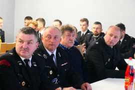 Grupa mężczyzn siedzących przy stole i przysłuchujących się rozmowie 