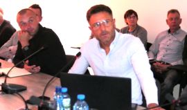 Mężczyzna siedzi przy stole i prezentuje projekt 