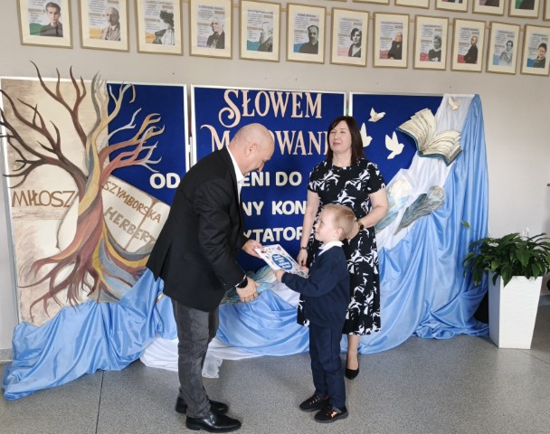 Mężczyzna wręcza małemu chłopcu dyplom 