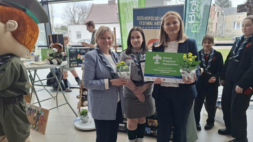 Trzy kobiety stoją obok siebie. Dwie z nich trzymają w ręku dyplomy 