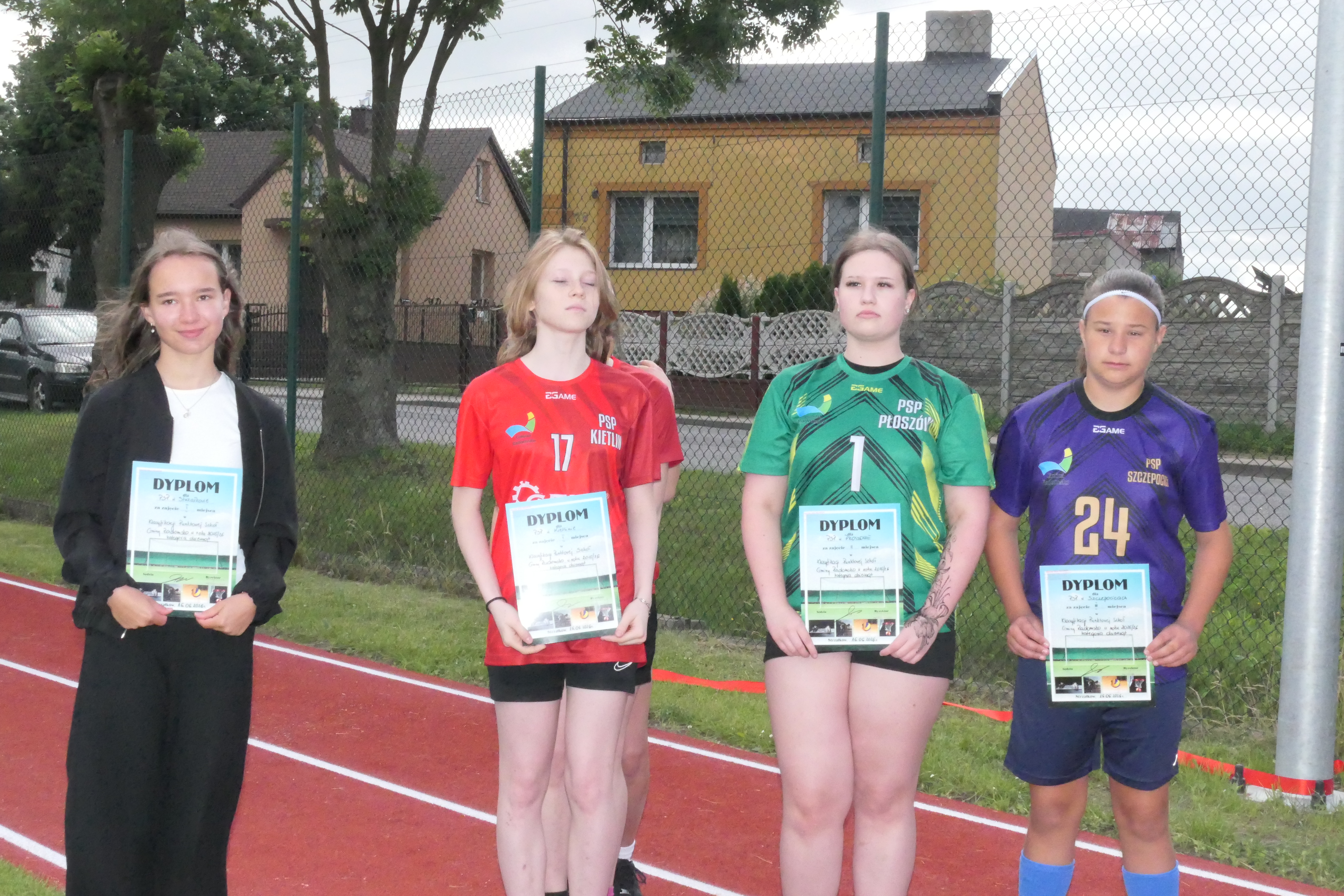 Cztery dziewczynki stoją obok siebie. Dziewczynki są ubrane w sportowe stroje oraz trzymają w dłoniach dyplomy 