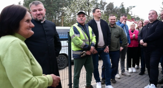 Grupa osób stoi obok siebie. Na pierwszy planie kobieta w zielonej bluzce i ksiądz 