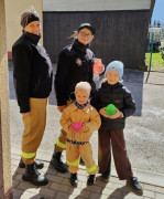 Dwie kobiety i dwoje małych siedzi stoją obok siebie. Osoby znajdują się na dworze 