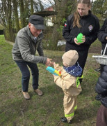 Małe dziecko podaje rączkę starszemu panu. Obok stoi kobieta 