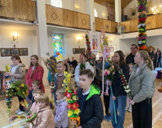 Wierni w kościele. Osoby trzymają w dłoniach palmy 