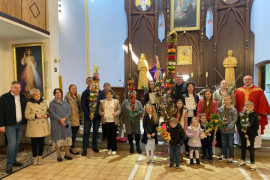 Grupa osób w kościele. Osoby trzymają w dłoniach palmy 