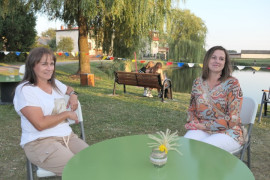 Dwie uśmiechnięte kobiety siedzące przy stoliku kawowym 