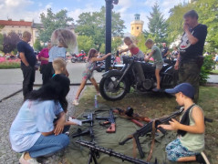 Dorośli i dzieci oglądają broń wystawione na stoisku wystawienniczym 