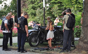 Osoby dorosłe i dzieci oglądają militaria wystawione na stoisku wystawienniczym 