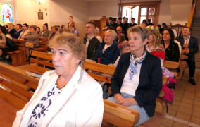 Osoby siedzą w ławkach 