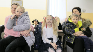 Dorośli i dzieci siedzą na krzesłach 