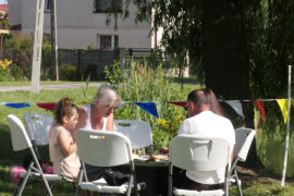 Osoby siedzą przy stoliku. Trwa rodzinny piknik 