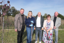 Osoby stoją obok siebie. Osoby te posadziły wspólnie drzewo 