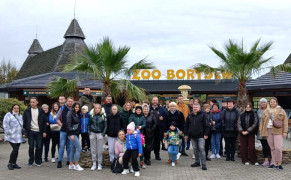 Grupa osób stojąca obok siebie. Za nimi znajduje się budynek z napisem ZOO Borysew 