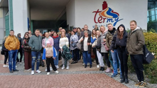 Grupa osób stoi przed budynkiem term w Uniejowie 