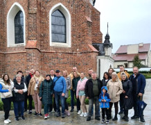 Grupa osób stojąca obok siebie. Osoby znajdują się w pobliżu zamku w Uniejowie 
