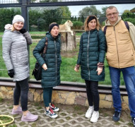Cztery osoby stojące na tle wybiegu dla lwów 