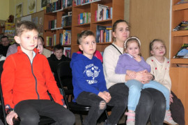 Grupa osób: dorośli i dzieci siedzą obok siebie na krzesłach