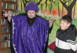 Kobieta w kolorowym ubraniu. Obok niej stoi uśmiechnięty chłopiec 