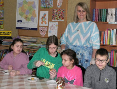 Trzy dziewczynki i chłopiec podczas przygotowywania babeczek. Towarzyszy im kobieta 