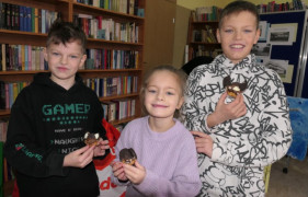 Dziewczynka i dwaj chłopcy prezentują wykonane przez siebie babeczki