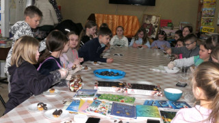 Dzieci: dziewczynki siedzą przy stole i przygotowują babeczki