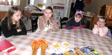 Cztery dziewczynki siedzą obok siebie przy stole 