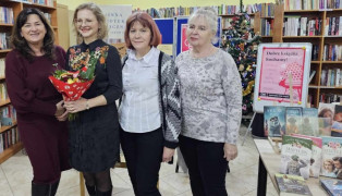 Cztery kobiety stoją obok siebie. Jedna trzyma w ręku bukiet kwiatów