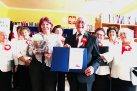 Grupa osób: kobiety i mężczyzna, członkowie chóru "Złota Nutka" oraz kierownik biblioteki w Strzałkowie 