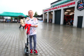 Chłopiec stojący przy hulajnodze, którą wygrał w konkursie