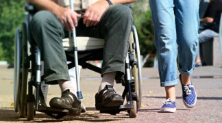 Osoba z niepełnosprawnością na wózku. Obok widoczna osoba pełnosprawna 