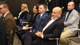 Kobiety i mężczyźni siedzą obok siebie na krzesłach. Osoby uczestniczą w spotkaniu 