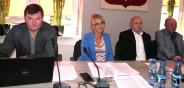 Cztery osoby, kobieta i trzech mężczyzn siedzą przy stole 