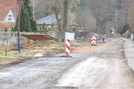 Rozkopana droga, przy której ustawione stoją biało-czerwone słupki