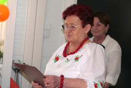 Dwie kobiety stoją obok siebie. Jedna z nich trzyma w ręku białe kartki papieru 