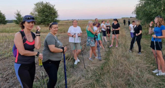 Grupa osób. Osoby trzymają w ręku kijki potrzebne do marszu Nordic Walking 