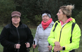 Trzy kobiety stojące obok siebie. Panie trzymają w dłoniach kijki Nordic Walking 