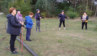 Grupa osób - rozgrzewka przed marszem Nordic Walking