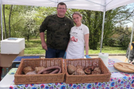 Kobieta i mężczyzna stoją obok siebie. Przed nimi znajduje się kosz z wędlinami 