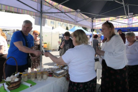 Stoisko wystawiennicze. Widać osoby kupujące i sprzedające 