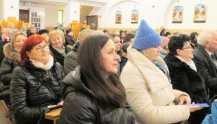 Osoby siedzą w kościelnych ławkach 