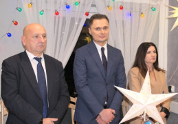 Spotkanie opłatkowe: kobieta i dwaj mężczyźni stoją przy stole 