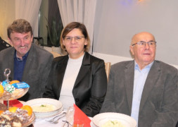 Spotkanie opłatkowe: kobieta i dwaj mężczyźni siedzą za stołem 