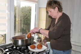 Kobieta wyciąga z garnka upieczone pączki