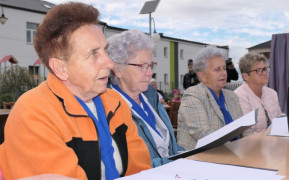 Cztery kobiety siedzą obok siebie i śpiewają 