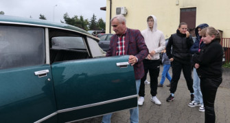 Grupa osób przy zabytkowym samochodzie 