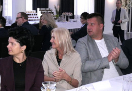 Dwie kobiety i mężczyzna siedzą obok siebie przy stole 