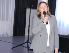 Kobieta podczas wystąpienia. Kobieta trzyma w ręku mikrofon 