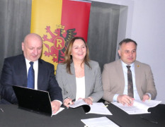 Trzy osoby siedzą przy stole. Moment podpisywania mowy